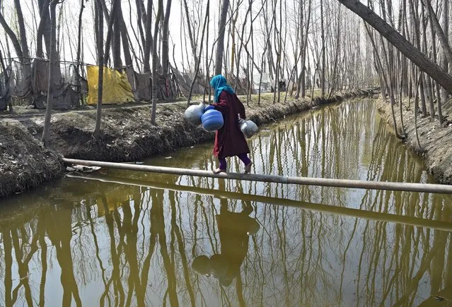 A Kashmiri Muslim woman balances on a water pipe before collecting water at Dasilpora village on March 22, 2018. World Water Day is held annually on 22 March as a means of focusing attention on the importance of freshwater and advocating for the sustainable management of freshwater resources. (Photo by Tauseef Mustafa/AFP Photo)