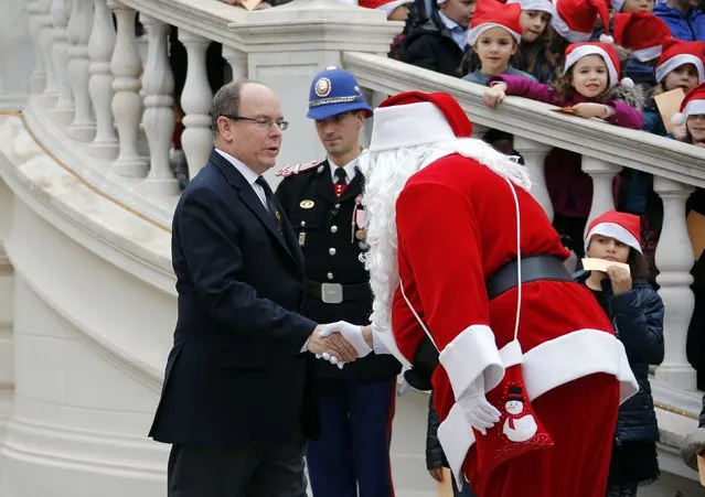 A man dressed as a Santa Claus greets Prince Albert II of Monaco (L) as he arrives to attend the traditional Christmas tree ceremony at the Monaco Palace as part of Christmas holiday season in Monaco, December 17, 2014. (Photo by Eric Gaillard/Reuters)