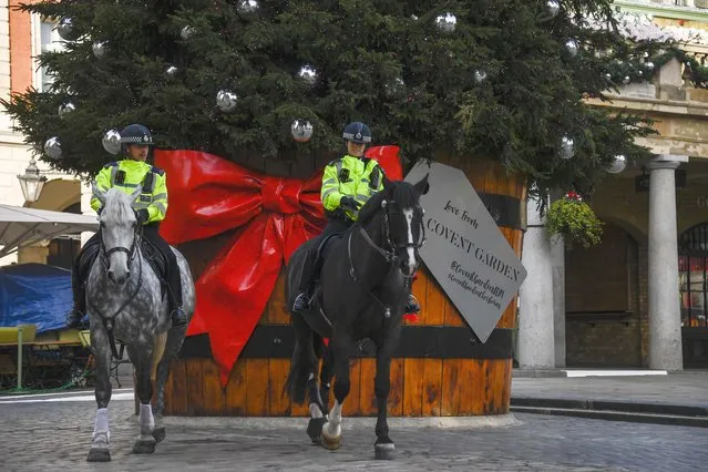 Two police officers ride their horses backdropped by a Christmas tree in Covent Garden, in London, Tuesday, November 24, 2020. Haircuts, shopping trips and visits to the pub will be back on the agenda for millions of people when a four-week lockdown in England comes to an end next week, British Prime Minister Boris Johnson said Monday. (Photo by Alberto Pezzali/AP Photo)