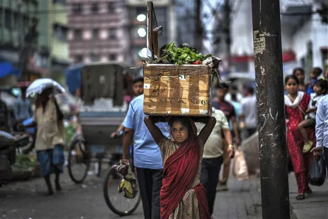A woman laborer carries garbage in a box on her head in market in Guwahati, India, Tuesday, March 14, 2023. (Photo by Anupam Nath/AP Photo)