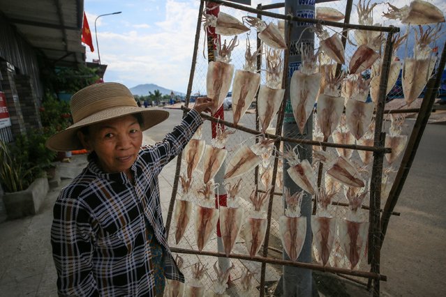 A woman holds a frame for dried fish near Nai Market (Du Khanh Market) stands out as the region's largest fishing village and seafood market in Khanh Hai town of Vietnam's Ninh Thuan province on July 08, 2025. From early morning, fresh catches brought in by fishing boats fill the market, where women both sell and dry seafood. After trading ends, villagers spend time playing traditional games. (Photo by Ummu Nisan Kandilcioglu/Anadolu via Getty Images)
