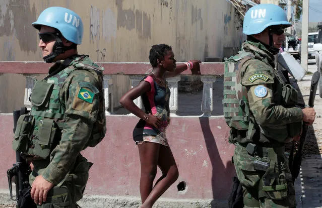 A woman stands next to two Brazilian peacekeepers as they secure the perimeter of the Lycee Philippe Guerrier before the visit of UN Secretary General Ban Ki Moon after Hurricane Matthew in Les Cayes, Haiti, October 15, 2016. (Photo by Andres Martinez Casares/Reuters)