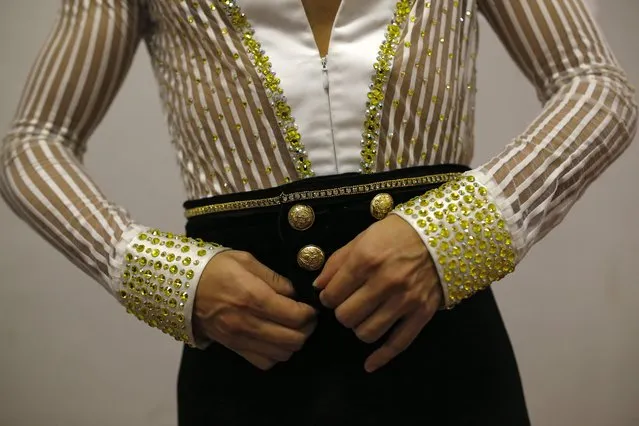 In this Friday, November 6, 2015 photo US' dancer Elvis Collado buttonhooks his outfit backstage before taking part in the World Salsa Master dance competition in Madrid. (Photo by Francisco Seco/AP Photo)