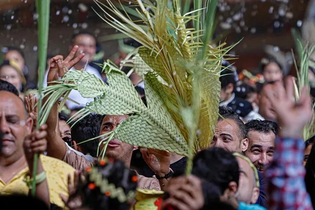 Egyptian Coptic Christians react as they get sprayed with holy water during Palm Sunday Mass at the Saint Simon Monastery, also known as the Cave Church, in Cairo's Mokattam mountain on April 9, 2023. (Photo by Khaled Desouki/AFP Photo)
