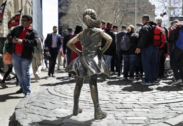 Tourists line up to get a view of the Charging Bull statue, behind the “Fearless Girl” sculptureat the foot of Broadway in the Financial District, Thursday, April 26, 2018, near Wall Street in New York. (Photo by Kathy Willens/AP Photo)