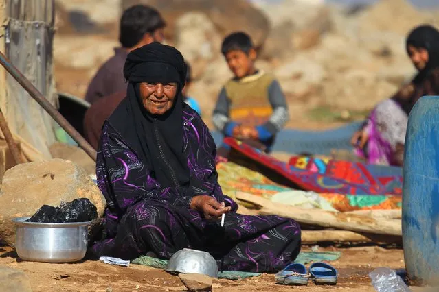 An internally displaced woman sits with others outside their tents at a makeshift refugee camp in Sinjar town, in Idlib province, Syria November 20, 2015. (Photo by Ammar Abdullah/Reuters)