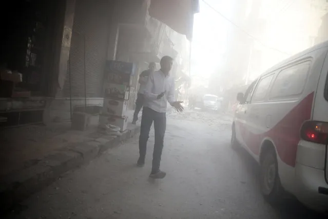 Men walk amidst dust after shelling in the rebel held besieged town of Douma, eastern Ghouta in Damascus, Syria October 20, 2016. (Photo by Bassam Khabieh/Reuters)