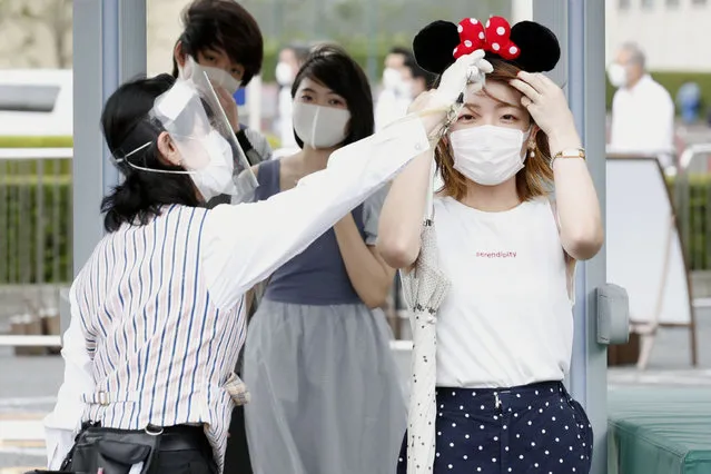 A visitor has her body temperature checked at the entrance of Tokyo Disneyland in Urayasu, near Tokyo, Wednesday, July 1, 2020. Tokyo Disneyland reopened for the first time in four months after suspending operations due to coronavirus concerns. (Photo by Kyodo News via AP Photo)