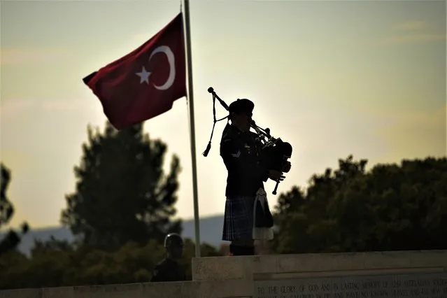 An Australian soldier plays the pipes next to a Turkish flag in a pole at half staff during a ceremony to commemorate at the Lone Pine following the Dawn Service ceremony at the Anzac Cove beach, the site of World War I landing of the ANZACs (Australian and New Zealand Army Corps) on April 25, 1915, in Gallipoli peninsula, near Canakkale, Turkey, Tuesday, April 25, 2023. Hundreds of people gathered by a beach near the former World War I battlefields on Turkey's Gallipoli Peninsula on Tuesday to pay homage to soldiers from Australia and New Zealand who lost their lives in a disastrous campaign 108 years ago. (Photo by Emrah Gurel/AP Photo)