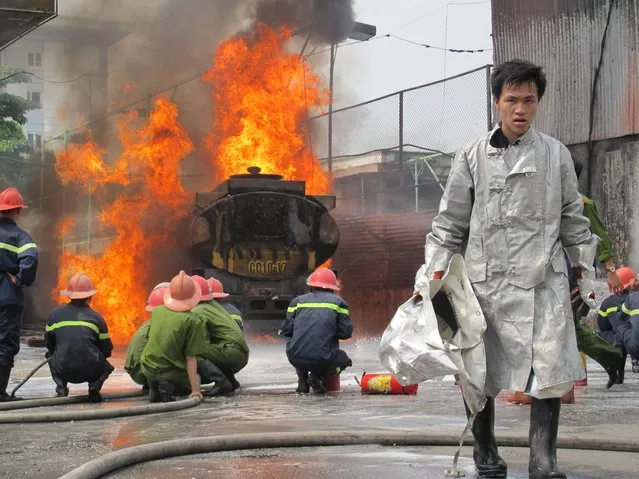 A Vietnamese fire fighter walks away from a blazing gas tanker as his colleagues try to control the fire in Hanoi, Vietnam, Monday, June 3, 2013. There were no injuries reported as a result of the fire, which apparently started from a car at the gas station. (Photo by Chris Brummitt/AP Photo)