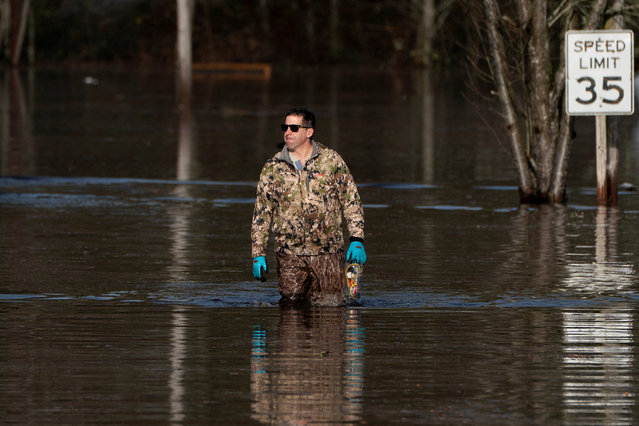 Drew Glastetter walks through floodwaters in an area flooded by the Snoqualmie River in Fall City, Washington, on December 9, 2025. (Photo by David Ryder/Reuters)