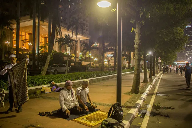 Two member of hard-line Islamic groups pray on a central street after a day of violent protest by islamic hardliners on November 4, 2016 in Jakarta, Indonesia. (Photo by Ed Wray/Getty Images)