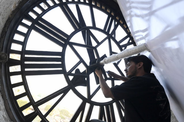 A local craftsman works on the dial of the historic clock tower at Empress Market in Karachi, Pakistan, 30 October 2025. Built in 1889 during the British Raj to honor Queen Victoria, the Indo-Gothic clock tower made of Gizri sandstone once guided colonial Karachi with its 153-kilogram bell, serving as a vital timekeeper when personal watches were a rarity. (Photo by Shahzaib Akber/EPA)