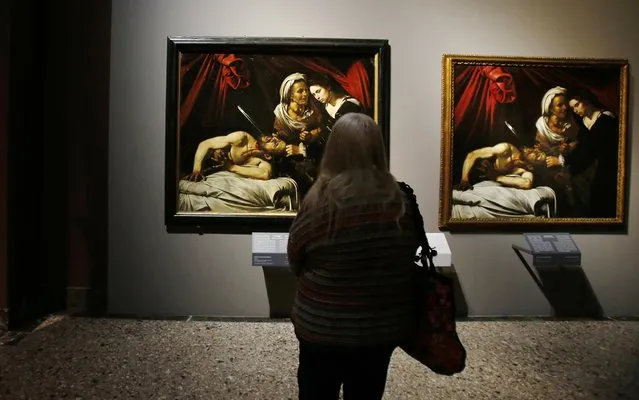 A woman looks at a painting believed to be the “Judith Beheading Holofernes” by the Italian baroque master Michelangelo Merisi da Caravaggio, left, and a copy by Flemish painter Louis Finson, at the Brera Art Gallery in Milan, Italy, Monday, November 7, 2016. The director of the Brera Art Gallery has courted controversy by including in a new show a painting whose  attribution to Caravaggio is disputed. Critics charge that the decision to  display “Judith Beheading Holofernes”, discovered two years ago in an attic in southern France, legitimizes the attribution to Caravaggio and would drive up the work's price were it to be put on the market. (Photo by Antonio Calanni/AP Photo)