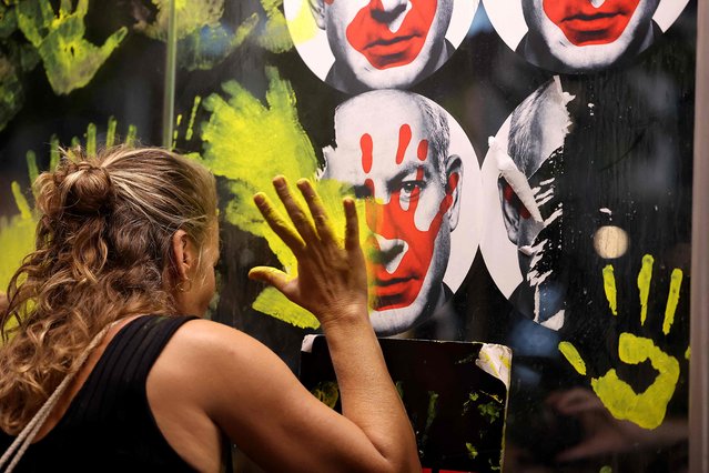 A woman defaces a picture of Prime Minister Benjamin Netanyahu with paint as Israeli anti-government demonstrators stage a protest calling for action to secure the release of Israeli hostages held captive since the October 7 attacks by Palestinian militants in the Gaza Strip, in front of the Israeli Defence Ministry in Tel Aviv on September 5, 2024, amid the ongoing war between Israel and the militant Hamas group. During the October 7 attack by Hamas on Israel, militants seized 251 people, 97 of whom are still held captive in Gaza, including 33 the military says are dead. (Photo by Jack Guez/AFP Photo)