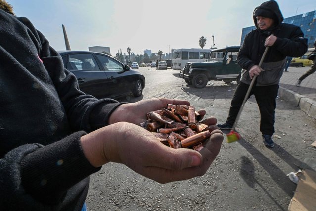 Men sweep the street to clear bullet shells at Umayyad Square in Damascus on December 10, 2024. Syria's Islamist rebel leader on December 9 began discussions on transferring power, a day after his opposition alliance dramatically unseated president Bashar al-Assad following decades of brutal rule. (Photo by Louai Beshara/AFP Photo)