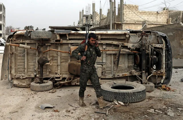 A member of Syrian Kurdish People's Defense Units (YPG) walks in front of a destroyed vehicle in Kobane, Syria, January 28, 2015. According to reports Kurdish fighters on January 28 claimed to have pushed militants from the group calling themselves the Islamic State (IS) out of the embattled Syrian town of Kobane, following four months of fighting, which included airstrikes carried out by an international anti-IS coalition. (Photo by Sedat Suna/EPA)