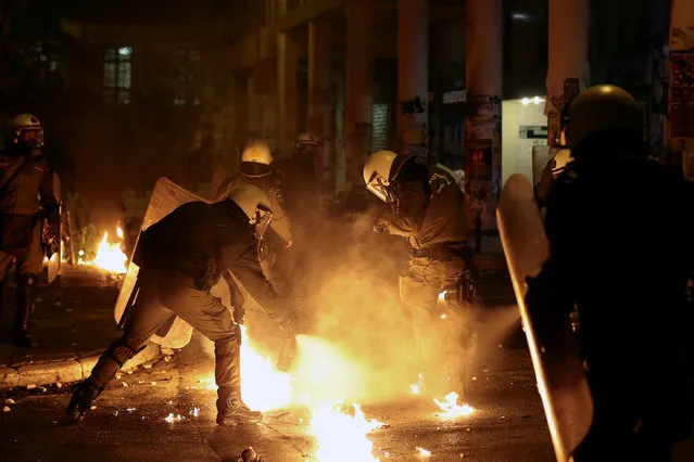 Riot policemen try to extinguish flames from a petrol bomb on a colleague during clashes following a rally marking the 43nd anniversary of a 1973 student uprising against the military dictatorship that was ruling Greece, in Athens, Greece, November 17, 2016. (Photo by Alkis Konstantinidis/Reuters)