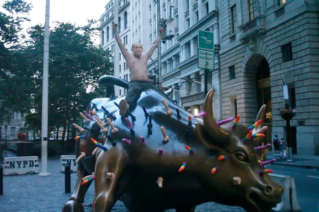 Activist Jeff Jetton, bare chested and wearing a mask to portray Russia's President Vladimir Putin, sits on the Wall Street bull sculpture covered with s*x toys in New York City on July 18, 2018. (Photo by Joe Fionda/@fiondavision via Reuters)