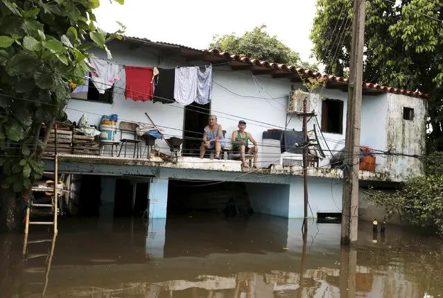 A family (top) sits in their house above flood waters in Asuncion, December 27, 2015. (Photo by Jorge Adorno/Reuters)