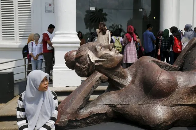 A student sits beside a sculpture by Indonesian artist Purjito at National Gallery in Jakarta during Christmas holiday on December 29, 2015. (Photo by Reuters/Beawiharta)