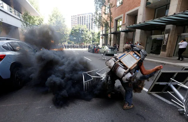 A counter-protester throws a smoke canister back towards police during a rally by the Patriot Prayer group in Portland, Oregon, U.S. August 4, 2018. (Photo by Bob Strong/Reuters)