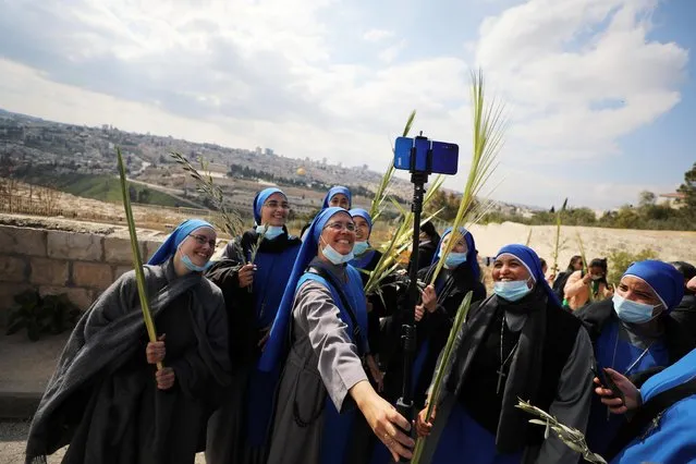 Christian nuns take a selfie while they hold palm fronds as they take part in a Palm Sunday procession on the Mount of Olives in Jerusalem on March 28, 2021. (Photo by Ammar Awad/Reuters)