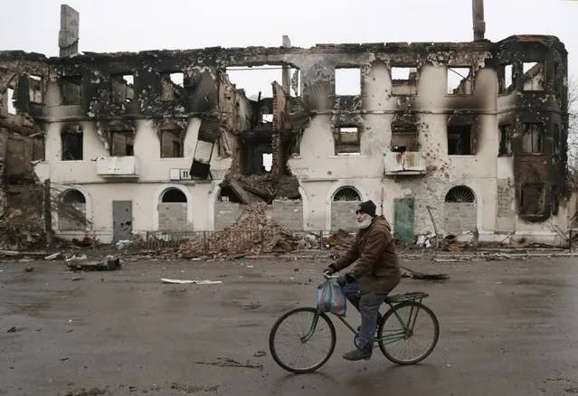 A resident rides his bicycle past a destroyed building in the town of Vuhlehirsk, Ukraine, Friday, February 6, 2015. (Photo by Petr David Josek/AP Photo)