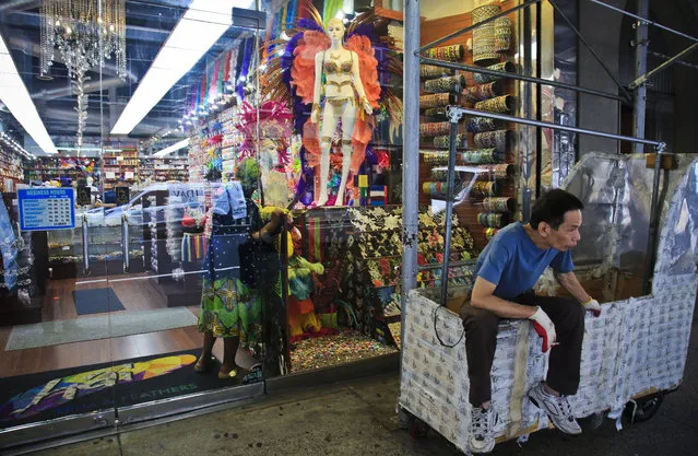 In this August 1, 2018 photo, a worker rest on a clothing rack cart outside a fashion and costume accessory store in New York's Garment District. A group of manufacturers, landlords, designers and politicians has a plan to preserve a remnant of the garment industry in a neighborhood where about 5,000 people are still employed in workshops mostly serving higher-end designers. (Photo by Bebeto Matthews/AP Photo)