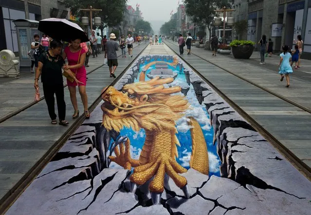 Chinese women look at a 3D painting of a dragon at Qianmen Street, a popular tourist spot in Beijing, China Sunday, August 11, 2013. (Photo by Andy Wong/AP Photo)