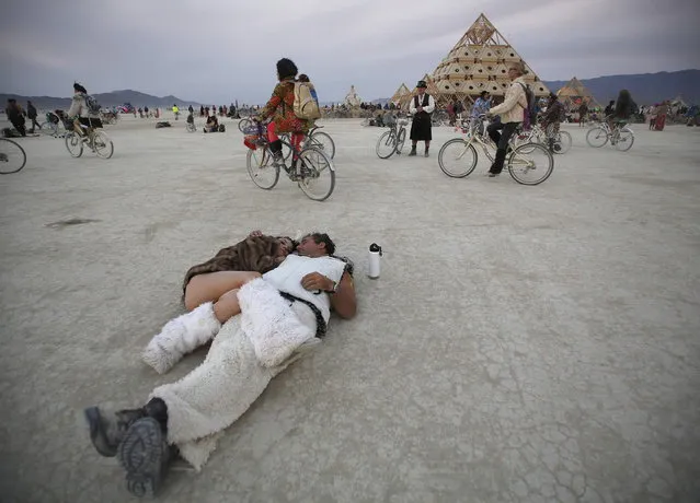 Participants cuddle at sunrise at the Temple of Whollyness during the Burning Man 2013 arts and music festival in the Black Rock Desert of Nevada, August 31, 2013. The federal government issued a permit for 68,000 people from all over the world to gather at the sold out festival, which is celebrating its 27th year, to spend a week in the remote desert cut off from much of the outside world to experience art, music and the unique community that develops. (Photo by Jim Urquhart/Reuters)