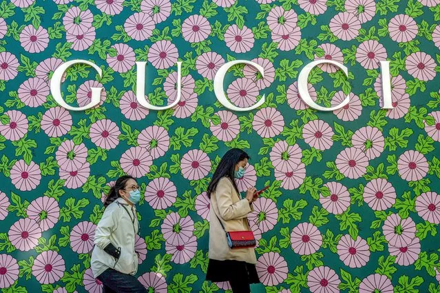 People walk past a Gucci shop on a street in Beijing on April 13, 2021. (Photo by Nicolas Asfouri/AFP Photo)