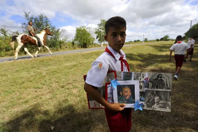 A child holds images of Cuba's late President Fidel Castro while awaiting the caravan carrying Castro's ashes in Las Tunas, Cuba, December 1, 2016. (Photo by Ivan Alvarado/Reuters)