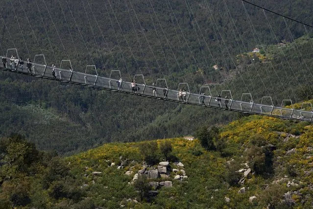 People walk across a narrow footbridge suspended across a river canyon, which claims to be the world's longest pedestrian bridge, in Arouca, northern Portugal, Sunday, May 2, 2021. (Photo by Sergio Azenha/AP Photo)