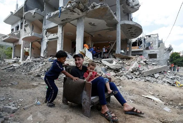 Palestinians sit on chair amid the rubble of a building which was damaged in Israeli air strikes during the Israel-Hamas fighting in Gaza on May 23, 2021. (Photo by Mohammed Salem/Reuters)