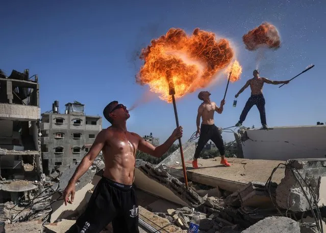 Palestinian members of Gaza's Bar Woolf sports team perform with fire above the ruins of a building destroyed in recent Israeli air strikes, in Beit Lahia, on May 26, 2021. A ceasefire was reached late last week after 11 days of deadly violence between Israel and the Hamas movement which runs Gaza, stopping Israel's devastating bombardment on the overcrowded Palestinian coastal enclave which, according to the Gaza health ministry, killed 248 Palestinians, including 66 children, and wounded more than 1,900 people. Meanwhile, rockets from Gaza claimed 12 lives in Israel, including one child and an Israeli soldier. (Photo by Mahmud Hams/AFP Photo)