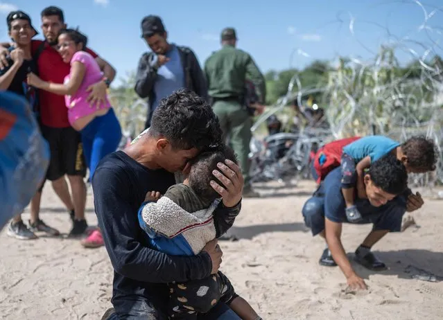 A migrant family from Venezuela reacts after breaking through a razor wire barricade into the United States, following hours of waiting on a river bank on the Rio Grande river, in Eagle Pass, Texas, on September 25, 2023. Dozens of migrants arrived at the US-Mexico border on September 22, 2023, hoping to be allowed into the United States, with US border forces reporting 1.8 million encounters with migrants in the last 12 months. (Photo by Andrew Caballero-Reynolds/AFP Photo)