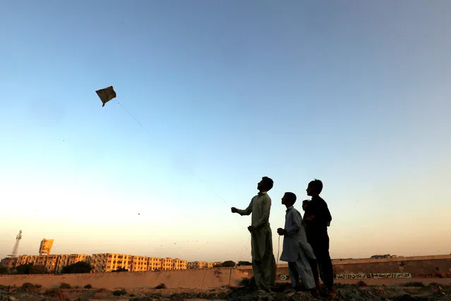 A boy with friends, flies a kite along the dry bed of Lyari River in Karachi, Pakistan October 23, 2018. (Photo by Akhtar Soomro/Reuters)