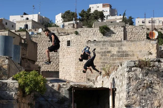 Palestinian youths (front to back) Abdallah al-Natsheh, Usaid Abu Khalaf, and Hammam Abu Sneineh practice parkour over roofs and stairways of traditional stone houses in the West Bank city of Hebron, on June 5, 2021. (Photo by  Hazem Bader/AFP Photo)