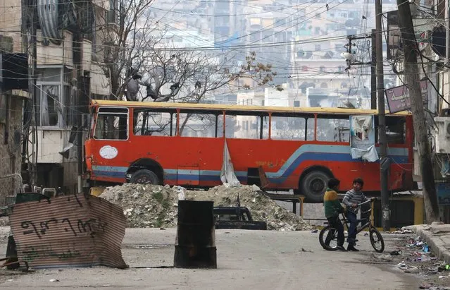 Children play near a bus barricading a street, which serves as protection from snipers loyal to Syria's President Bashar al-Assad, in Aleppo's rebel-controlled Bustan al-Qasr neighbourhood January 28, 2015. (Photo by Abdalrhman Ismail/Reuters)