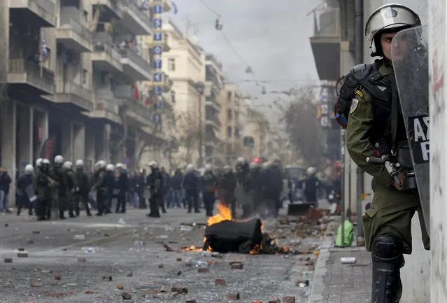 A riot policeman takes cover from incoming stones outside the Agriculture ministry following clashes between Greek farmers from the region of Crete and police during a protest against planned pension reforms in Athens, Greece February 12, 2016. (Photo by Yannis Behrakis/Reuters)