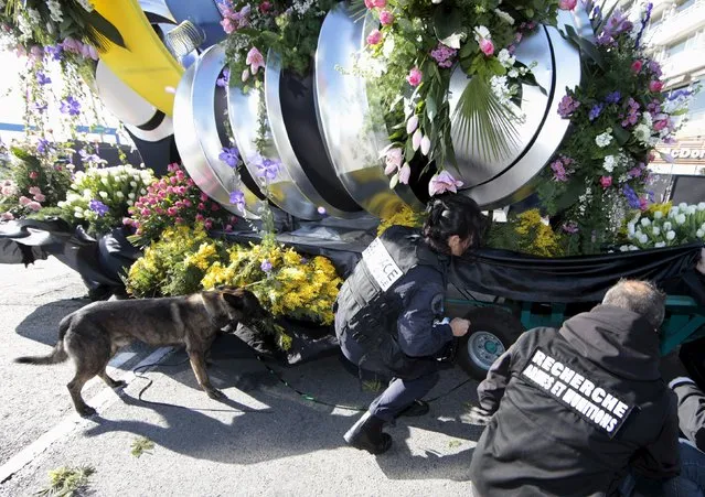 Police officers use a sniffer dog for a security check on a float of the flower parade as part of the Carnival in Nice, France, February 13, 2016. (Photo by Eric Gaillard/Reuters)