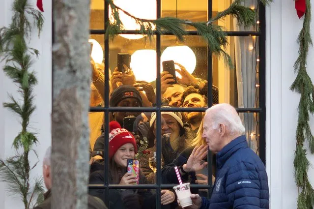 Onlookers watch and cheer from inside a store as U.S. President Joe Biden walks past while shopping with family members, in Nantucket, Massachusetts, U.S, November 25, 2023. (Photo by Tom Brenner/Reuters)