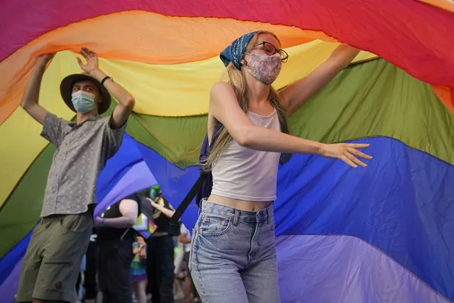 Participants wave a rainbow flag during the gay pride march n Bucharest, Romania, Saturday, August 14, 2021. (Photo by Vadim Ghirda/AP Photo)