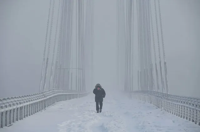 A man walks on the Vinogradovsky Bridge across the Yenisei River, as the air temperature plunges as low as minus 35 degrees Celsius (minus 31 degrees Fahrenheit), in the Siberian city of Krasnoyarsk, Russia on December 12, 2023. (Photo by Alexander Manzyuk/Reuters)