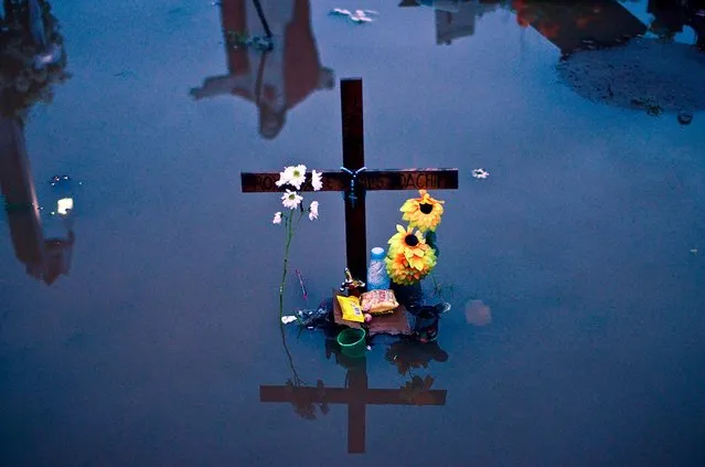 Flowers are left at a flooded mass grave, where victims of Super Typhoon Haiyan are buried, Tacloban, Leyte, Philippines, on December 24, 2013. Haiyan has been described as one of the most powerful typhoons ever to hit land, leaving thousands dead and hundreds of thousands homeless. With Christianity being the predominant religion in Philippines, the people of Tacloban will try to find a way to celebrate Christmas despite the incredibly difficult circumstances. (Photo by Dondi Tawatao/Getty Images)