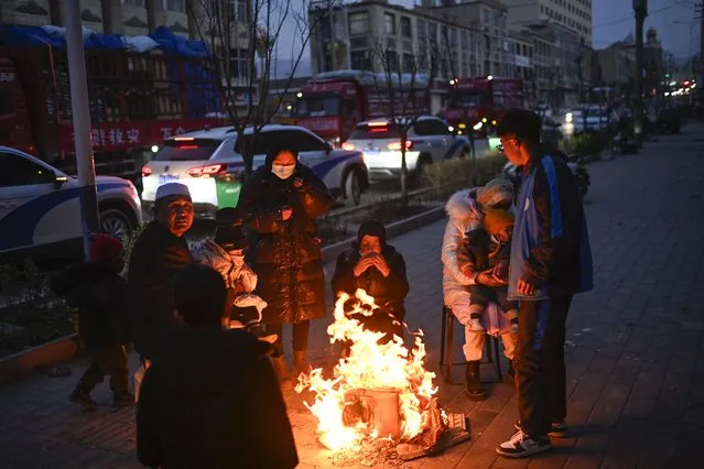 People gather next to a fire on a street after an earthquake in Dahejia, Jishishan County in northwest China's Gansu province on December 19, 2023. (Photo by Pedro Pardo/AFP Photo)
