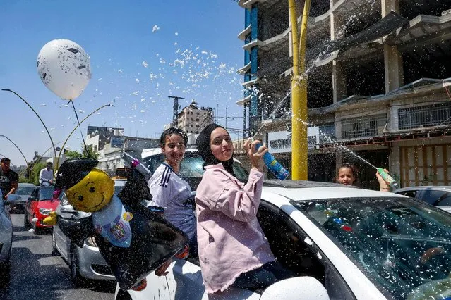 Palestinian high school students spray foam from a car window as they celebrate on the street after passing their final exams known as “Tawjihi”, in the West Bank city of of Hebron, on August 3, 2021. (Photo by Hazem Bader/AFP Photo)