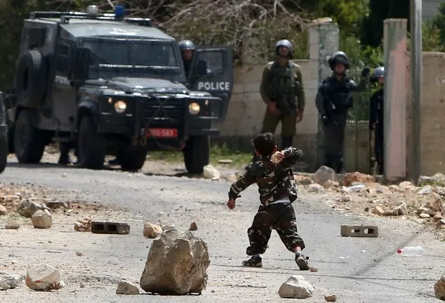 A Palestinian child throws a stone towards Israeli forces during clashes between Palestinian protestors and security forces following a demonstration in support of Palestinian men imprisoned in Israeli jails and against the expropriation of land by Israel, on April 17, 2015 in the village of Kfar Qaddum, near Nablus in the occupied West Bank. (Photo by Jaafar Ashtiyeh/AFP Photo)