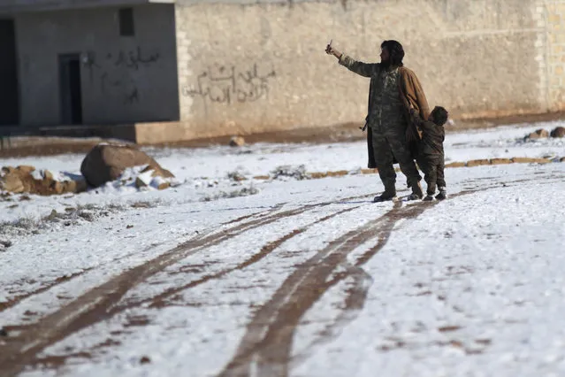 A rebel fighter takes a selfie with a boy on snow-covered ground in al-Rai town, northern Aleppo countryside, Syria January 28, 2017. (Photo by Khalil Ashawi/Reuters)